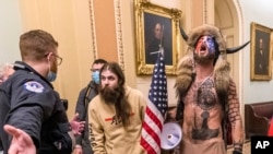 FILE - In this Jan. 6, 2021 file photo, supporters of President Donald Trump, including Jacob Chansley, with fur hat, are confronted by US Capitol Police officers outside the Senate Chamber inside the Capitol in Washington.