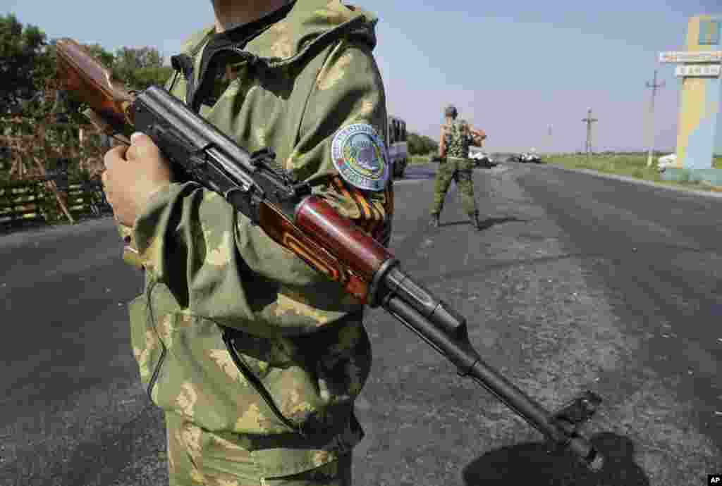 Pro-Russian rebels stand at a security post where at least 12 militiamen fighting on the side of the Ukrainian government were killed, on the outskirts of Donetsk, eastern Ukraine, Aug. 13, 2014.