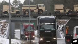 FILE - American military vehicles are transported by train across a bridge in Zagan, Poland, Jan. 12, 2017. 