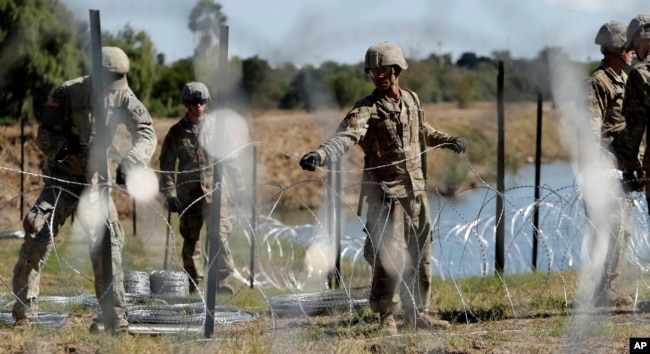 FILE - In this Nov. 16, 2018, photo, members of the U.S. military install multiple tiers of concertina wire along the banks of the Rio Grande near the Juarez-Lincoln Bridge at the U.S.-Mexico border in Laredo, Texas.