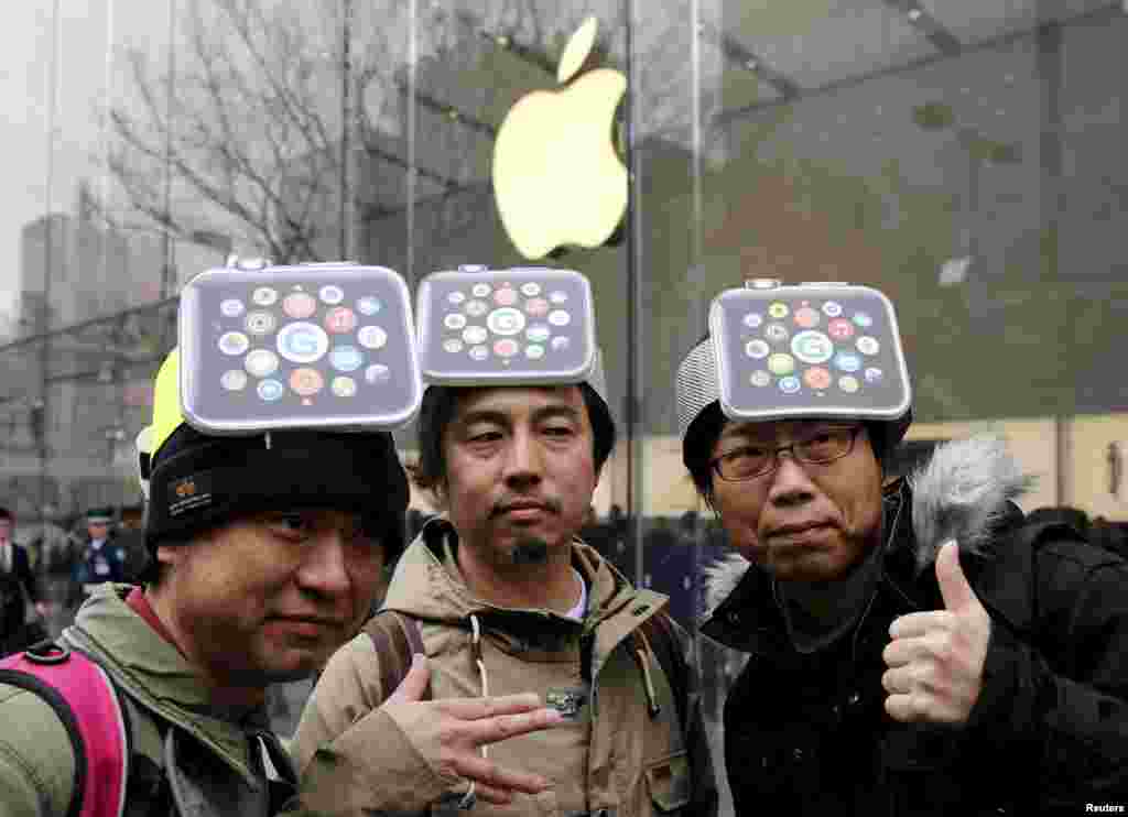 Men wearing cardboard hats depicting the Apple Watch, pose for photos before it goes on display in front of the Apple Store in Tokyo&#39;s Omotesando shopping district. Apple expects tremendous interest for its new smartwatch and demand to outstrip supply as consumers got an up-close look on Friday.