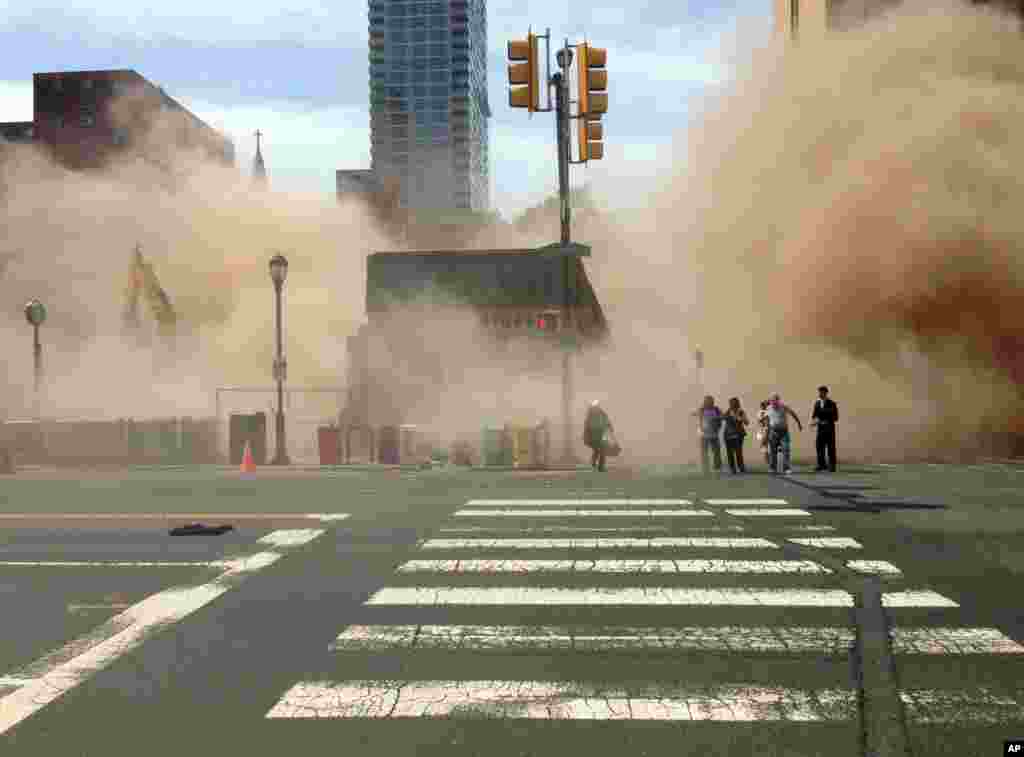 In this photo provided by Jordan McLaughlin, a dust cloud rises as people run from the scene of a building collapse on the edge of downtown Philadelphia, Pennsylvania, June 5, 2013. 