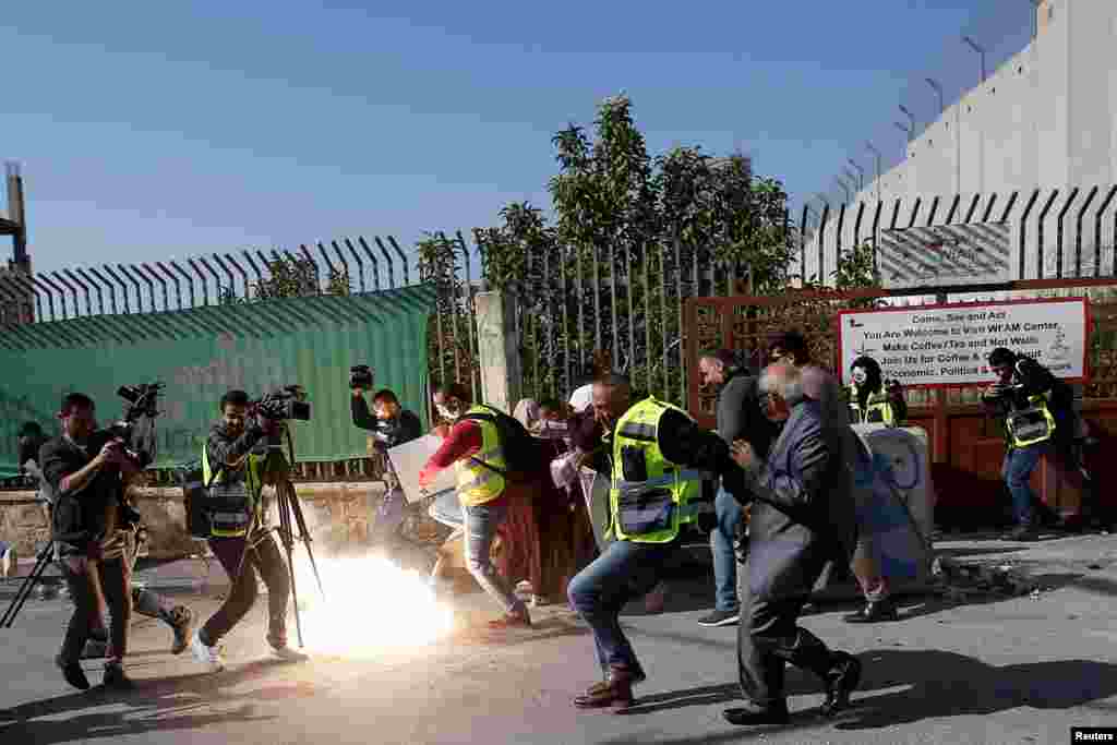 Palestinian journalists react to a stun grenade fired by Israeli forces during a protest to show solidarity with their colleague Muath Amarna, who was shot in his eye, in Bethlehem in the Israeli-occupied West Bank.