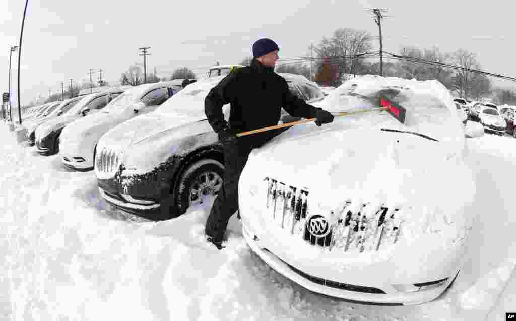 Matt Frame limpa a neve de um automóvel da marca Buick no Stand de automóveis Ray Laethem Buick-GMC em Detroit, Michigan, Jan. 6, 2014.