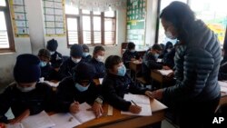 Students and a teacher wear masks as a precautionary measure at Matribhumi school in Bhaktapur, Nepal, Wednesday, Jan. 29, 2020. There has been one confirmed case of a new coronavirus infection in the Himalayan country. (AP Photo/Niranjan Shrestha)