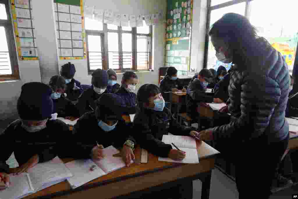 پوشش ماسک صورت به دلیل شیوع جهانی ویروس کرونا، توسط یک معلم و شاگردانش در مدرسه&zwnj;ای در باکتاپور، نپال
