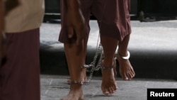 FILE - The shackled legs of suspected human traffickers are seen as they arrive for their trial at the criminal court in Bangkok, Thailand, March 15, 2016.