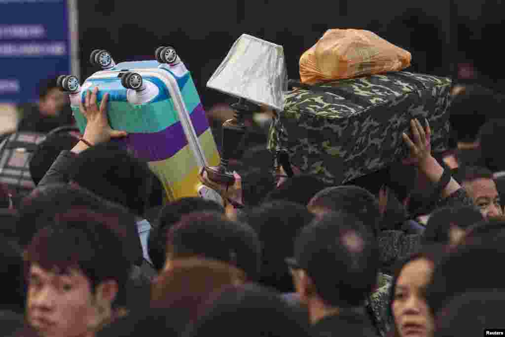 People carry their belongings at the main railway station in Guangzhou, Guangdong province, China, as travel for the annual Chinese Lunar New Year and Spring Festival holidays continues.