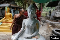 Jeremy, a Buddhist monk from Australia, inspects a Buddha statue at a workshop at the rehabilitation and detox area at Wat Thamkrabok monastery in Saraburi province, Thailand.