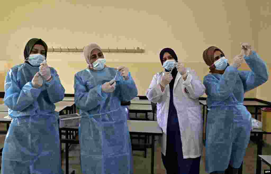 Palestinian health ministry workers prepare doses of the Sinopharm COVID-19 coronavirus vaccine, donated by the Chinese government, at a school in Halhoul, north of Hebron in the occupied West Bank.
