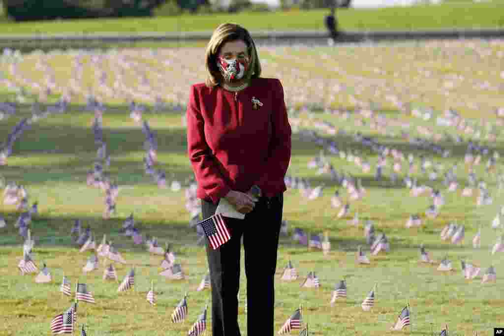 House Speaker Nancy Pelosi looks at small flags placed on the grounds of the National Mall by activists from the COVID Memorial Project to mark the deaths of 200,000 lives lost in the U.S. to COVID-19, in Washington, D.C.