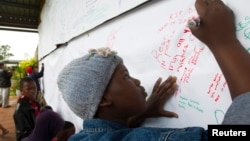 A child writes a note to former South African President Nelson Mandela on a banner at the Nelson Mandela Museum in Qunu, Dec. 12, 2013.
