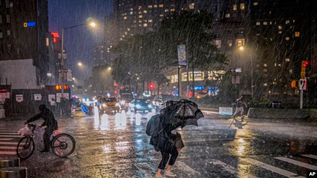 FILE - People travel through a torrential downpour caused from the remnants of Hurricane Ida, near Columbus Circle Wed. Sept. 1, 2021.
