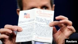 FILE - U.S. Treasury Secretary Timothy Geithner holds up a copy of the U.S. Constitution before reading a passage from the 14th Amendment at the Newseum in Washington, May 25, 2011. 