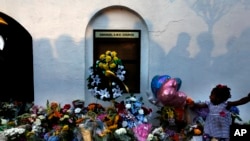 FILE - Mourners pass by a make-shift memorial on the sidewalk of in front of the Emanuel AME Church following a shooting in Charleston, S.C., June 18, 2015.