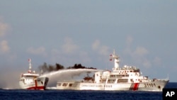 FILE - Image released by Vietnam Coast Guard, a Chinese coast guard vessel, right, fires water cannon at a Vietnamese vessel off the coast of Vietnam. 
