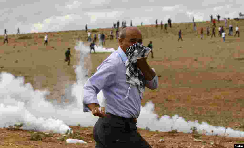 A Turkish Kurd protester runs away from tear gas fired by riot police near the Turkish-Syrian border in the southeastern town of Suruc in Sanliurfa province.