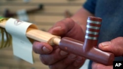 Travis Erickson holds a handmade pipe that he carved and crafted from pipestone, which is sold in his shops, on Wednesday, May 3, 2023, in Pipestone, Minn. (AP Photo/Jessie Wardarski)