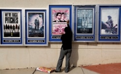 소니 영화사에 대한 북한의 사이버 공격으로 영화 '인터뷰' 개봉이 전격 취소된 가운데, 2014년 12월 17일 미국 아틀란타의 한 극장에서 영화 '인터뷰' 포스터를 내리고 있다.