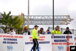 Pekerja pelabuhan melakukan aksi mogok di depan pintu masuk terminal peti kemas dekat Pelabuhan Boston di Boston, Selasa, 1 Oktober 2024. (Steven Senne/AP)