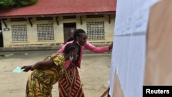 Women search for their names on a voter registration list at a polling station during the presidential election in Brazzaville, Republic of Congo, March 21, 2021. 