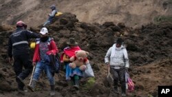 Residentes caminan en un área barrida por un deslizamiento de tierra en Alausí, Ecuador, el 28 de marzo de 2023, después de que una avalancha enterró decenas de casas y mató al menos a siete personas.