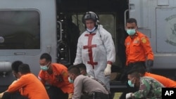 Tim SAR membawa tubuh korban AirAsia QZ8501 setelah diangkat oleh helikopter AL AS milik USS Sampson di Pangkalan Bun, Indonesia, Minggu, 4 Januari 2015. (AP Photo/Tatan Syuflana)