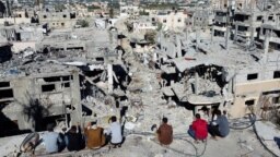 Warga Palestina melihat rumah-rumah yang hancur akibat serangan Israel selama konflik, di tengah gencatan senjata sementara antara Israel dan Hamas, di kamp pengungsi Khan Younis, di selatan Jalur Gaza, 29 November 2023. (Foto: REUTERS/Mohammed Salem)