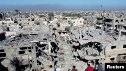 Palestinians look at the houses destroyed in Israeli strikes during the conflict, at Khan Younis refugee camp