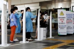 FILE - Visitors wearing masks to avoid the spread of COVID-19 fill out a form which is mandatory to get into a hospital in Seoul, South Korea, Aug. 26, 2020.
