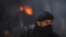 A fighter from the Islamist Syrian rebel group Jabhat al-Nusra in front of a burning vehicle, caused by what activists said were missiles fired by a Syrian Air Force fighter jet in Raqqa province, Syria, May 12, 2013.