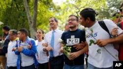 FILE - Venezuelan opposition leader Juan Guaido, center, walks with students at the Central University of Venezuela after a meeting with them in Caracas, Nov. 14, 2019. 