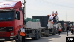 Workers from the Palestinian Red Crescent unload lorries carrying humanitarian aid after they entered the Gaza Strip from Egypt via the Rafah border crossing on October 21, 2023.