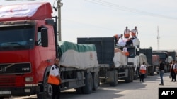 Trabalhadores do Crescente Vermelho Palestino descarregam camiões que transportam ajuda humanitária depois de entrarem na Faixa de Gaza vindos do Egipto através da passagem de fronteira de Rafah, 21 de outubro de 2023.