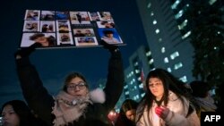 Seorang perempuan menunjukkan foto salah satu korban kecelakaan pesawat terbang Ukrainian Airlines dengan nomor penerbangan 752 yang jatuh di Iran, dalam doa bersama di Lapangan Mel Lastman di Toronto, Kanada, 9 Januari 2020. (Foto: AFP)