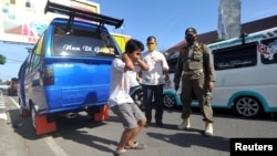 Seorang pria dikenai sanksi karena tidak mengenakan masker saat pembatasan sosial berskala besar untuk mencegah penyebaran virus corona di Padang, Sumatera Barat, 15 Mei 2020. (Foto: Antara via Reuters)