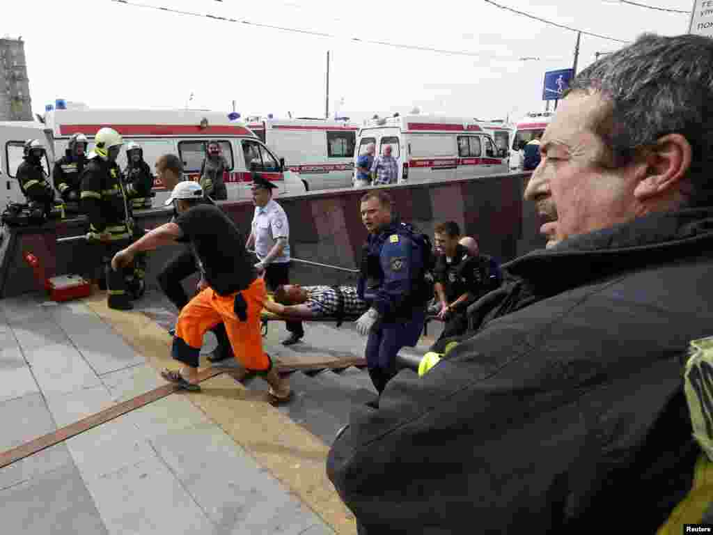 Para anggota layanan darurat membawa penumpang yang terluka di luar stasiun kereta di Moskow (15/7). (Reuters/Sergei Karpukhin)