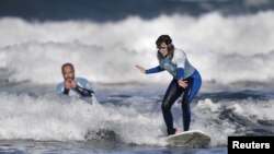 Carmen Lopez Garcia, atlet selancar air putri tuna netra Spanyol, yang akan berkompetisi di turnamen ISA World Adaptive Surfing Championship, sedang berlatih bersama pelatihnya Lucas Garcia, di pantai Salinas, Spanyol, 6 Desember 2018.