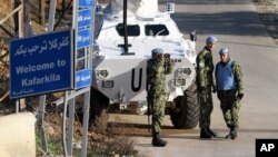 FILE - A Serbian U.N. peacekeeper looks through binoculars to monitor the border with Israel.