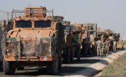 Turkish soldiers stand near military trucks in the village of Yabisa, near the Turkish-Syrian border, Syria, Oct. 12, 2019.