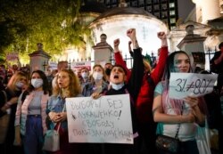 People, some of them ethnic Belarusians, hold a poster reading "Elections without Lukashenka! Freedom for political prisoners" and shout anti-Lukashenko slogans, Aug. 11, 2020.