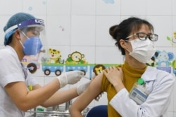 A woman receives a vaccine as Vietnam starts its official rollout of AstraZeneca's coronavirus vaccine for health workers, at Hai Duong Hospital for Tropical Diseases, Hai Duong province, Vietnam, March 8, 2021.