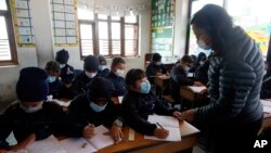 Students and a teacher wear masks as a precautionary measure at Matribhumi school in Bhaktapur, Nepal, Wednesday, Jan. 29, 2020. There has been one confirmed case of a new coronavirus infection in the Himalayan country. (AP Photo/Niranjan Shrestha)