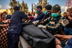 Medical volunteers move a bag carrying the body of a man killed during Turkish shelling in the area surrounding the Syrian Kurdish town of Ras al-Ayn as it arrives at a hospital in the nearby town of Tal Tamr, Oct. 18, 2019.