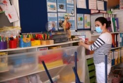 French coordinator Julie Bonaz covers a bookshelf with plastic to help provide a teaching environment safe from coronavirus for pupils and teachers at La Petite Ecole Bilingue at Kentish Town, north London, May 20, 2020.