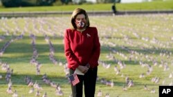House Speaker Nancy Pelosi looks at small flags put on the grounds of the National Mall by activists from the COVID Memorial Project to mark the deaths of 200,000 lives lost in the U.S. to COVID-19, in Washington, D.C.
