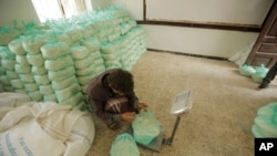 FILE - A worker weighs food aid from the World Food Program for distribution, in Sanaa, Yemen, Aug. 25, 2019. The U.N. humanitarian chief in Yemen warned that unless significant new funding is received, food rations for 12 million people will be reduced.