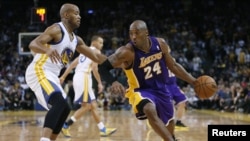 Pemain Los Angeles Lakers Kobe Bryant (kanan) menggiring bola basket, dijaga oleh Jarrett Jack dari Golden State Warriors pada pertandingan NBA Desember 2012. (Reuters/Stephen Lam)