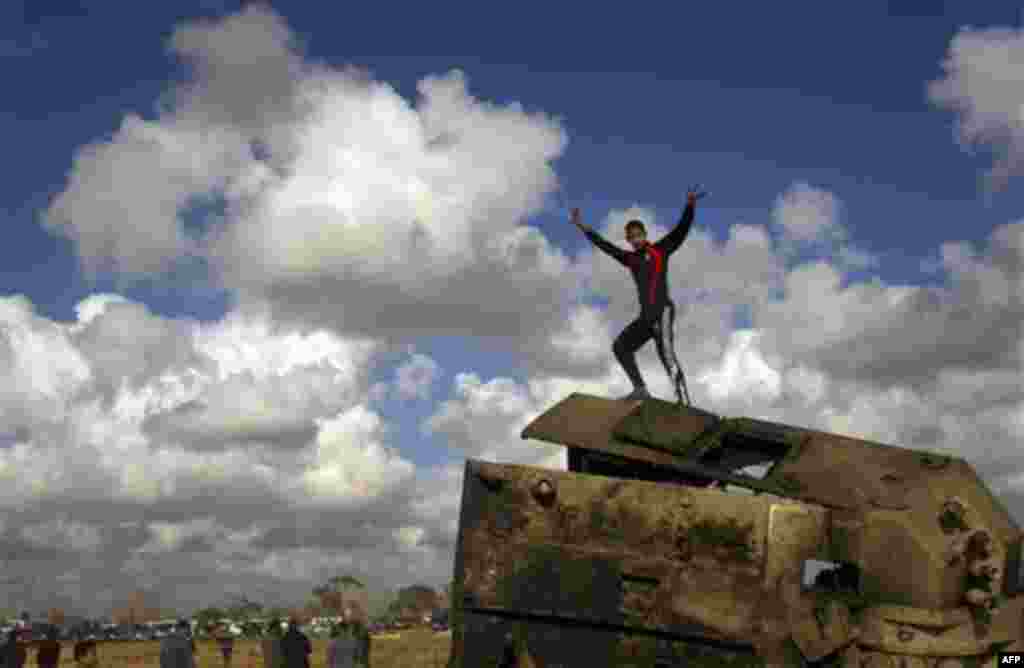 A Libyan boy reacts while standing on top of a destroyed military vehicle belonging to the forces of Moammar Gadhafi in the outskirts of Benghazi, eastern Libya, Sunday, March 20, 2011. (AP Photo/Anja Niedringhaus)