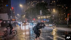 FILE - People travel through a torrential downpour caused from the remnants of Hurricane Ida, near Columbus Circle Wed. Sept. 1, 2021. 